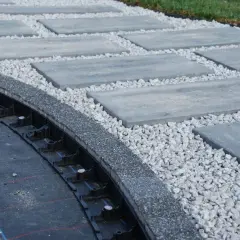 Obrzeże z kostki brukowej w trakcie montażu. Widoczna forma, geowłóknina i kruszywo.