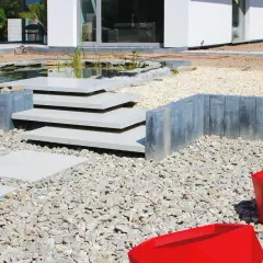 Nowe schody do ogrodu zrób sam, z kamienia i betonu, prowadzą do oczka wodnego.