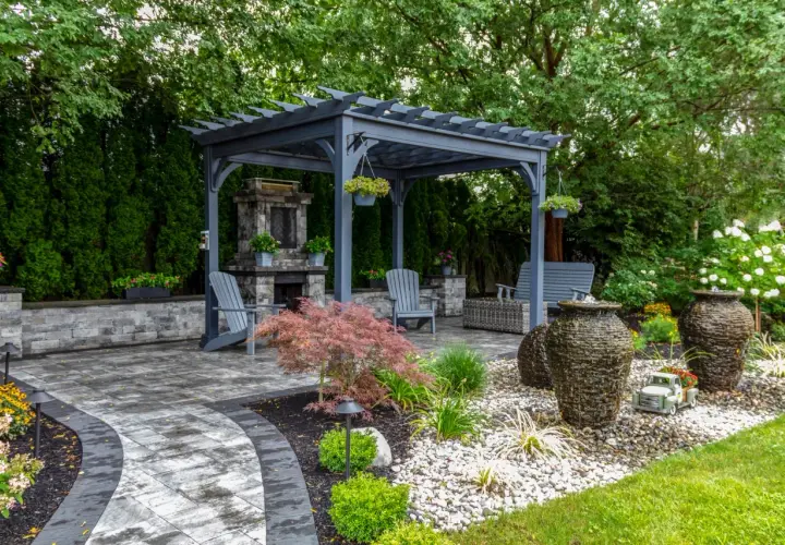 Idealny pomysł na kącik wypoczynkowy w ogrodzie: pergola, kamienny kominek, wygodne fotele i fontanny.