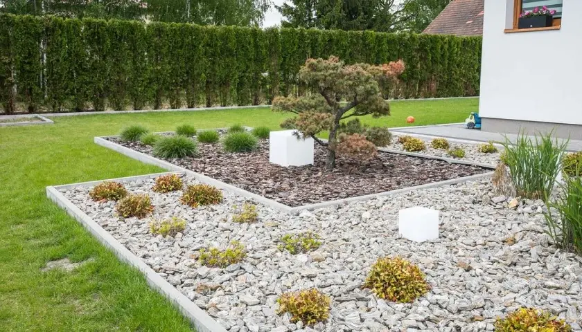 Nowoczesne klomby ogrodowe wzory z kamienia i kory, z bonsai i białymi sześcianami.