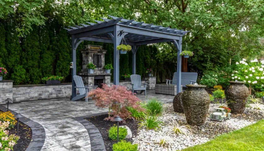 Idealny pomysł na kącik wypoczynkowy w ogrodzie: pergola, kamienny kominek, wygodne fotele i fontanny.