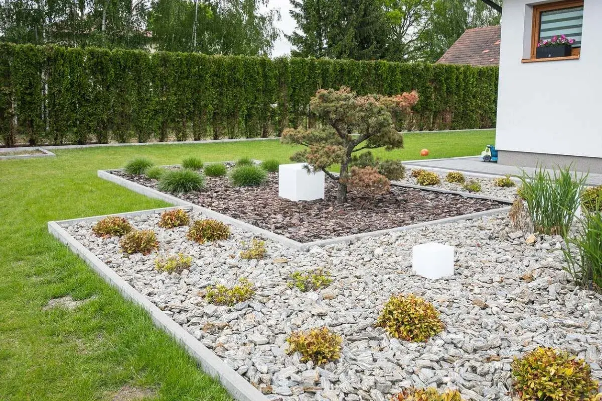 Nowoczesne klomby ogrodowe wzory z kamienia i kory, z bonsai i białymi sześcianami.