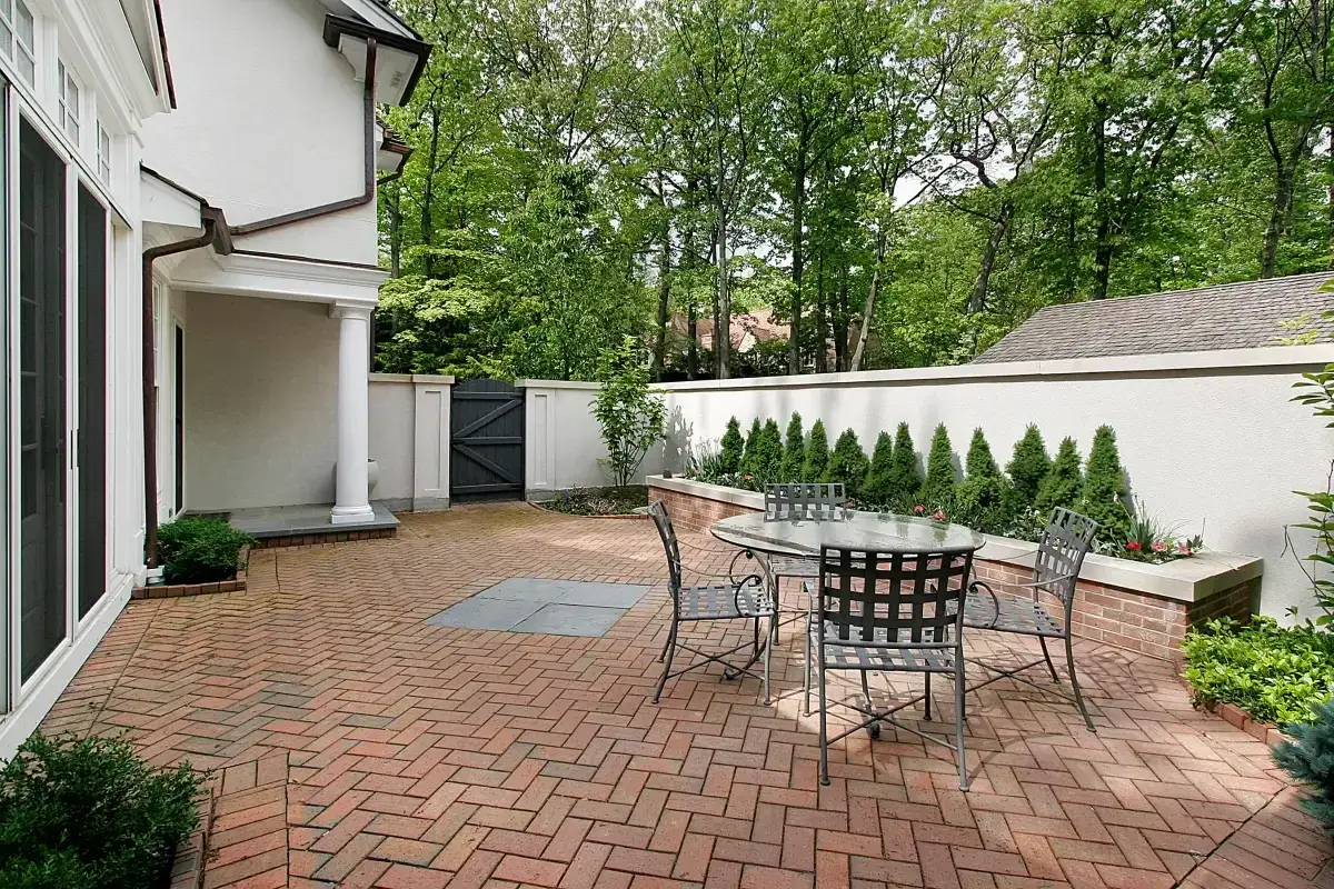 Patio z cegły, stary mur z cegły w ogrodzie, st&oacute;ł i krzesła.
